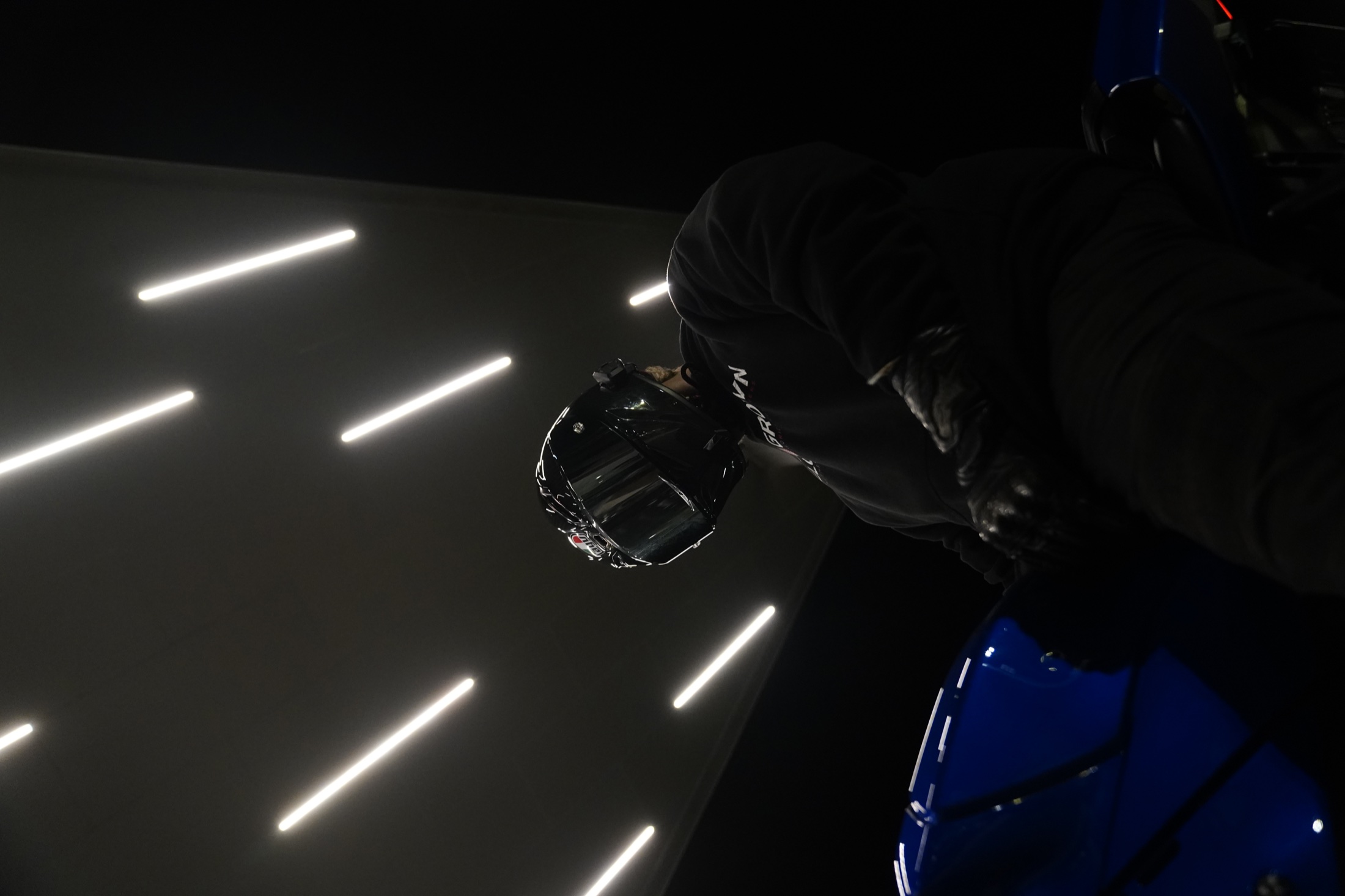 Helmeted rider photographed beneath linear lights