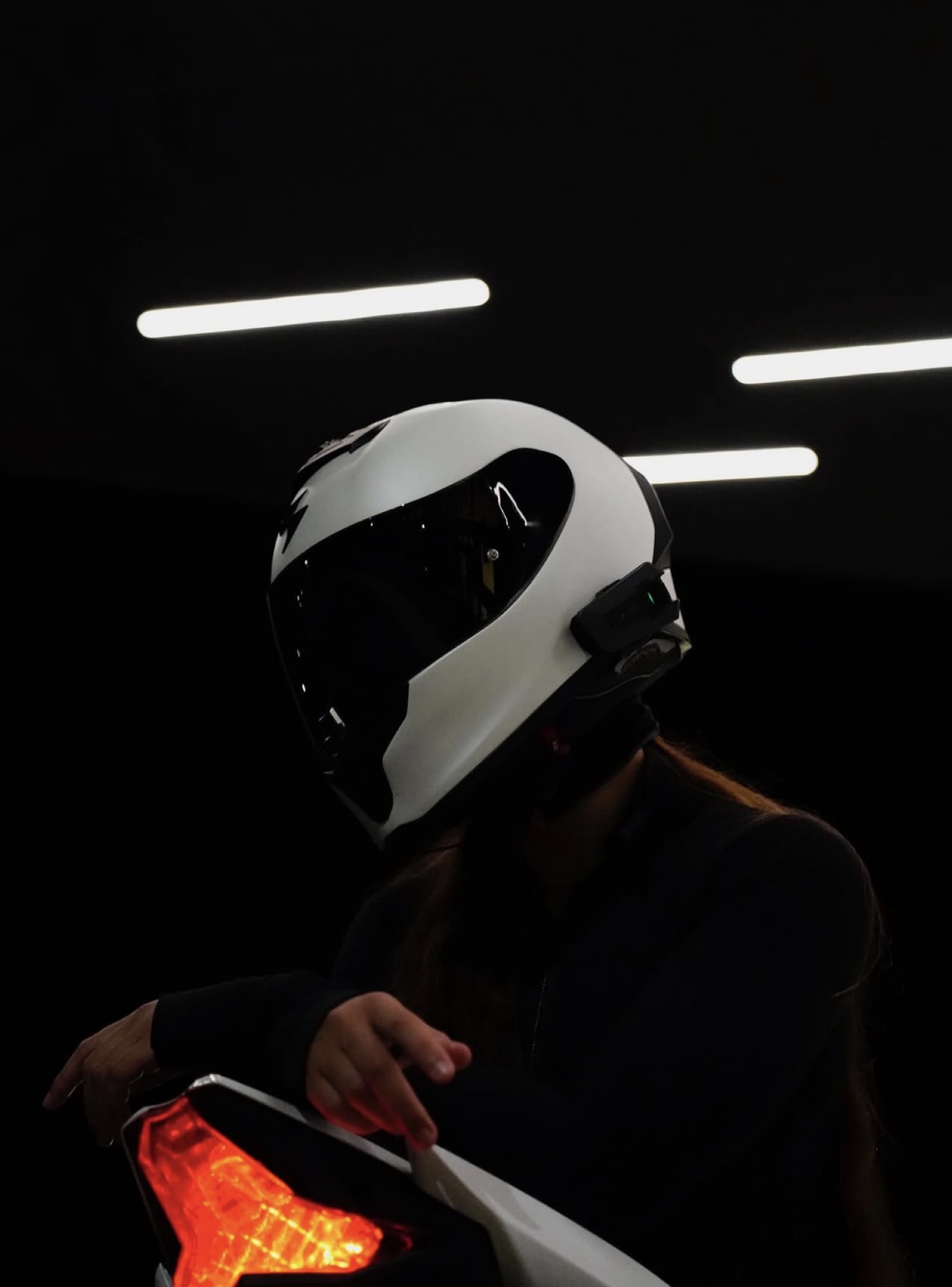 Rider in a white helmet beside a glowing tail light