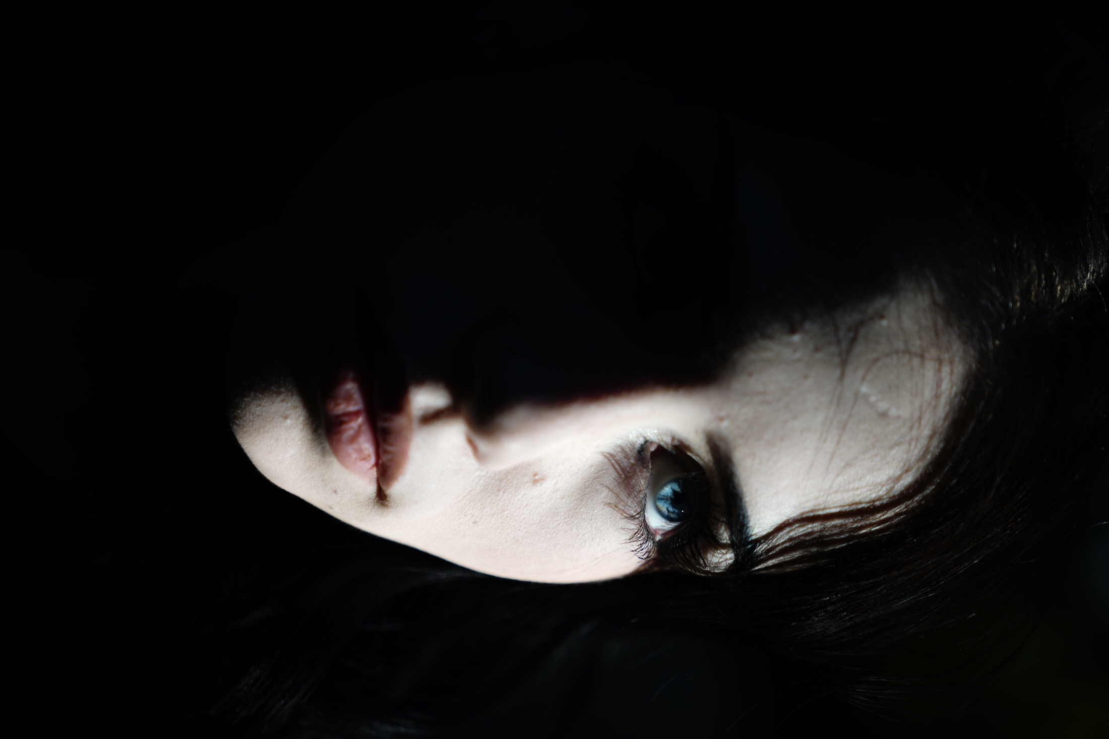 Low-key close portrait with one eye in the light